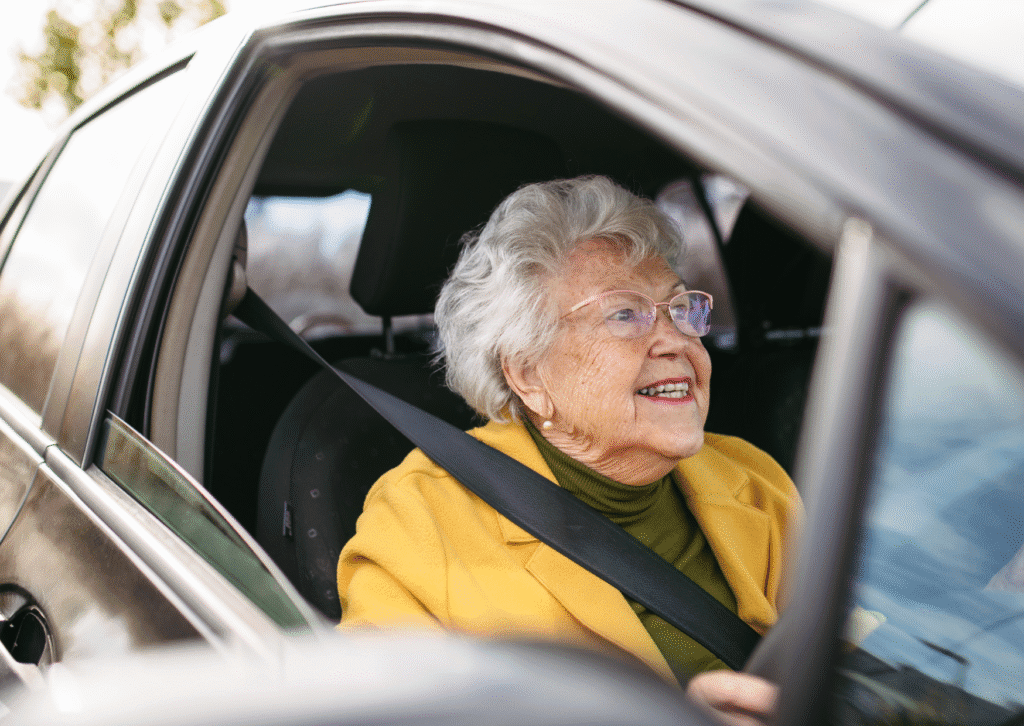 Happy senior woman driving car alone, enjoying car ride. Safe driving for elderly adults, older driver safety.