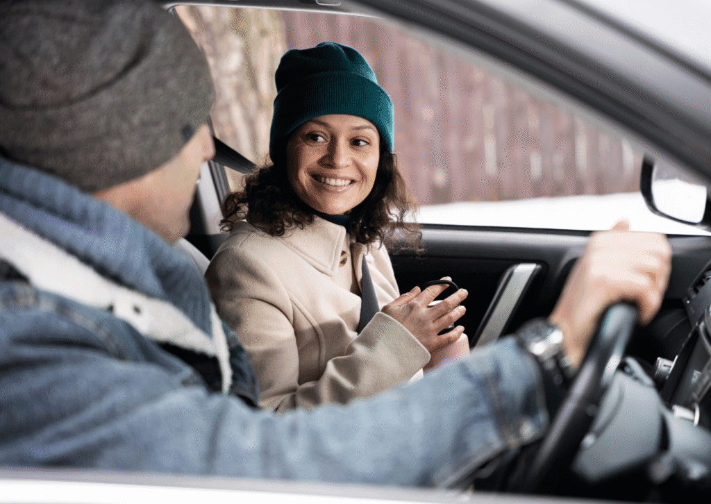 Two friends smiling in a car during winter travel.