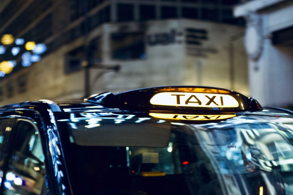 Taxi with illuminated rooftop sign at night.
