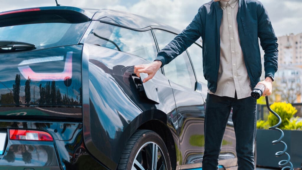 Man closing car's charge socket and holding charger at charge station